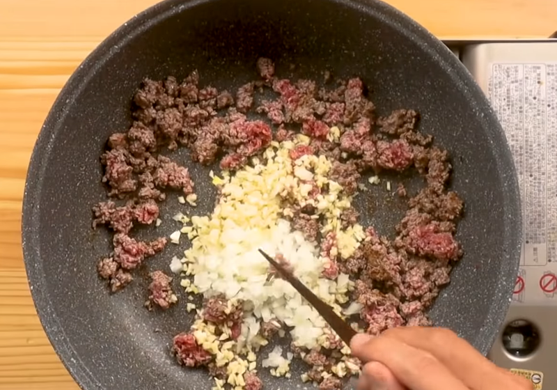 【餡料】乾鍋下牛絞肉，炒香至油脂釋出、稍微偏乾，放入洋蔥末、蒜末同炒，再加入紅葡萄酒炒勻。