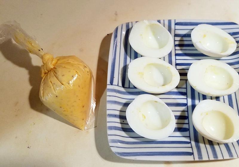 蛋黃挖出放入塑膠袋內，加入拌料混勻碾碎，將塑膠袋綁緊，在尖角處剪一缺口，即可擠入蛋白內，灑上辣椒粉即完成。