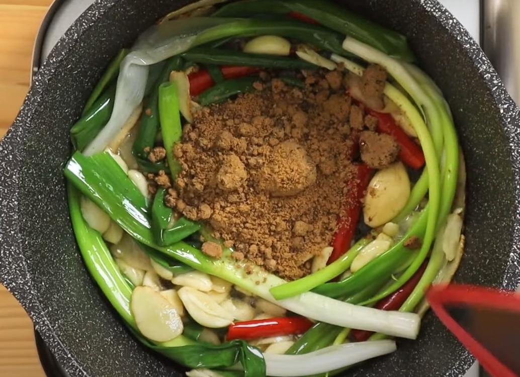 取深鍋,加入香油先小火爆香薑片約3分鐘,接著放入青蔥、蒜仁跟辣椒爆香3分鐘,再來加入黑糖拌炒出醬色。