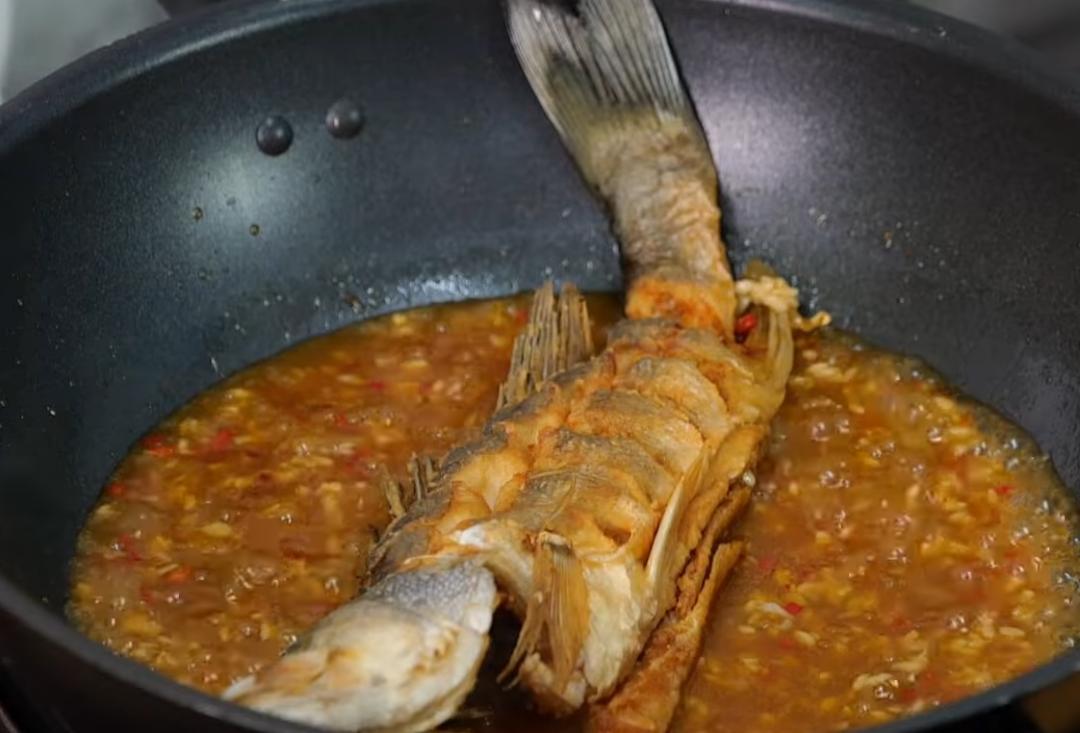續加醬油、高湯、泡椒、酒釀、糖略煮一下，加入太白粉水勾芡，醋沿著鍋邊淋一圈提香，將炸好的鱸魚入鍋燴煮約3-4分鐘（中間將魚翻面），起鍋前加入香菜即完成。