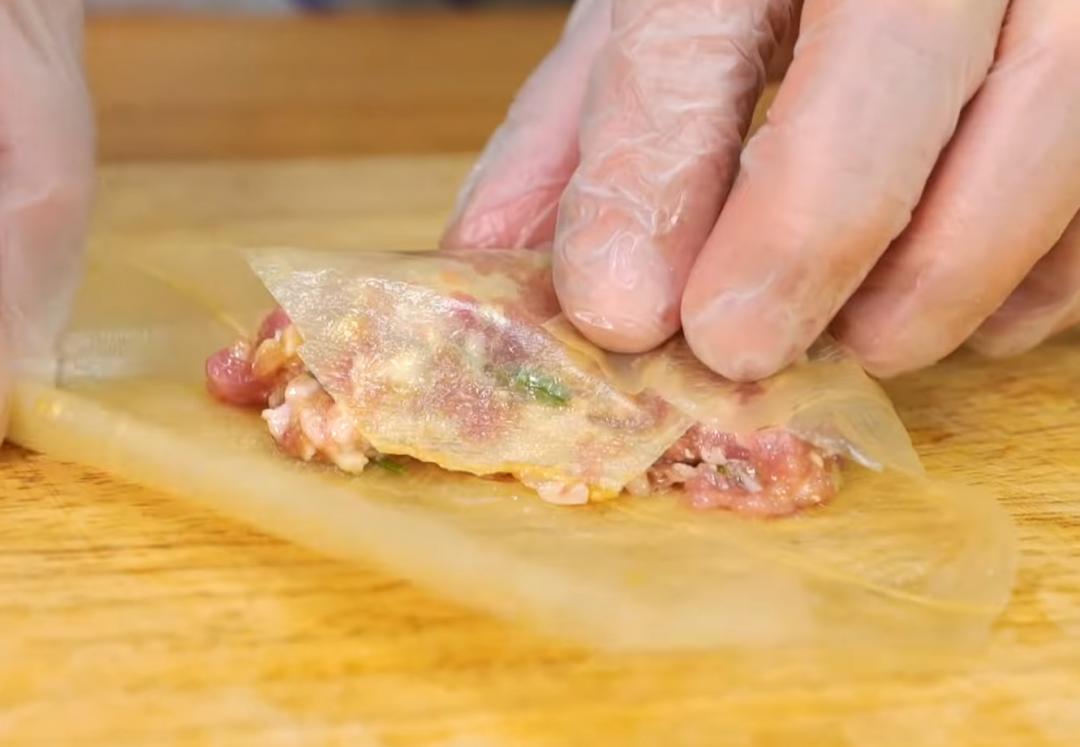 腐皮剪成正方形，中間放入拌好的肉餡，下方蓋起，接著左右向內折，捲起時收口處沾水幫助沾黏，捲成長方形，依此步驟製作肉捲。