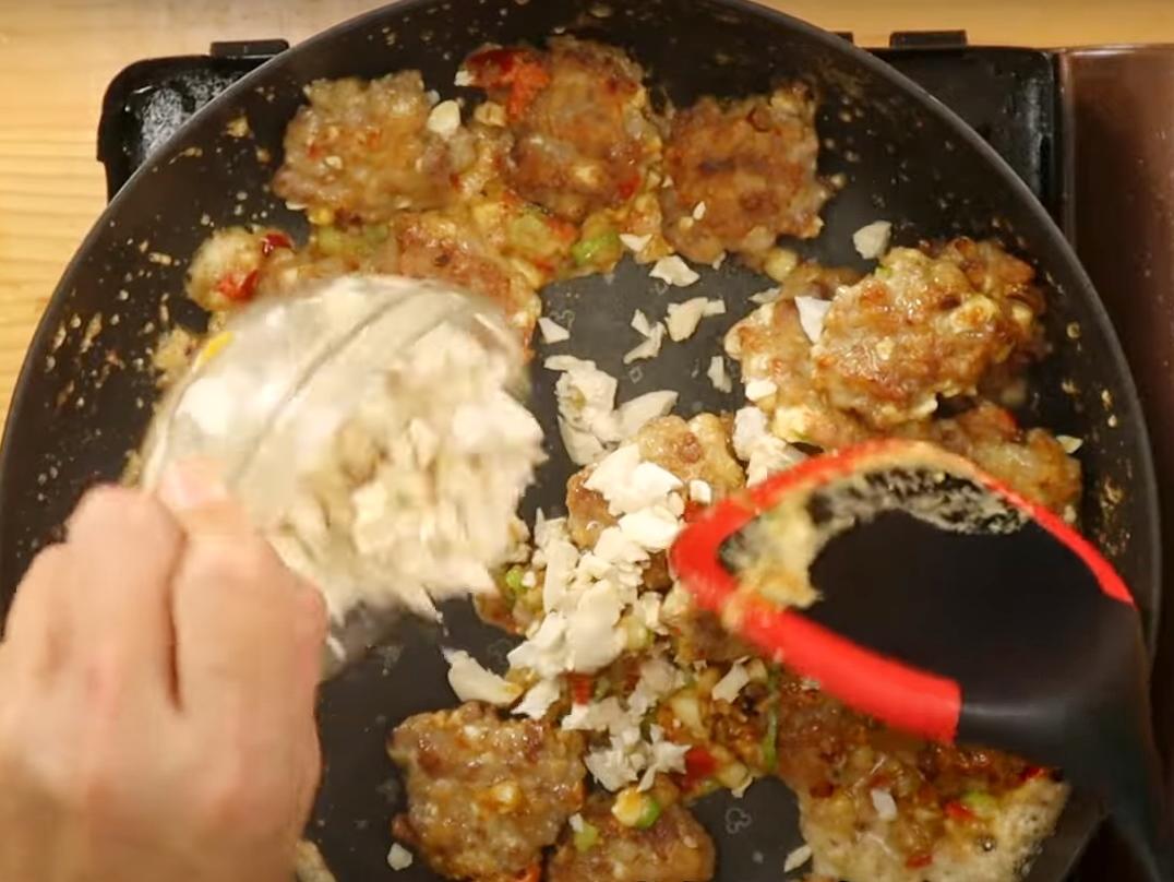 接著放入剩餘青蔥、辣椒、蒜仁炒香，將煎好的肉餅和適量鹹蛋白放入快速拌勻，即可起鍋。