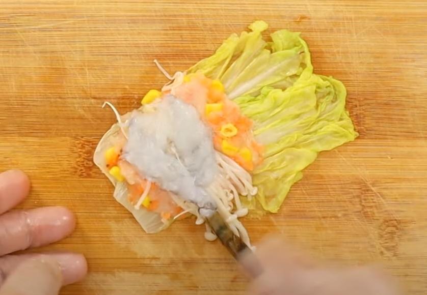 取兩片娃娃菜葉，放上一匙雞肉泥、金針菇、蝦子（蝦尾露在外面）捲起來。
