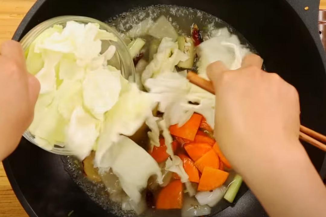 接著加入高湯（或開水）紅蘿蔔片、高麗菜一起煮軟。