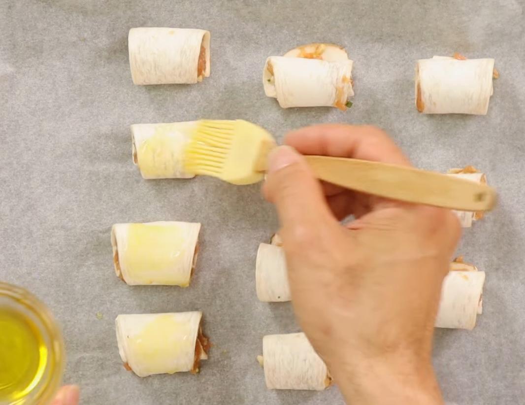 杏鮑菇捲起，收口處朝下放在鋪有烘焙紙的烤盤中，噴上少許油，進烤箱以攝氏180度烤15分鐘，途中翻面烤上色即完成。