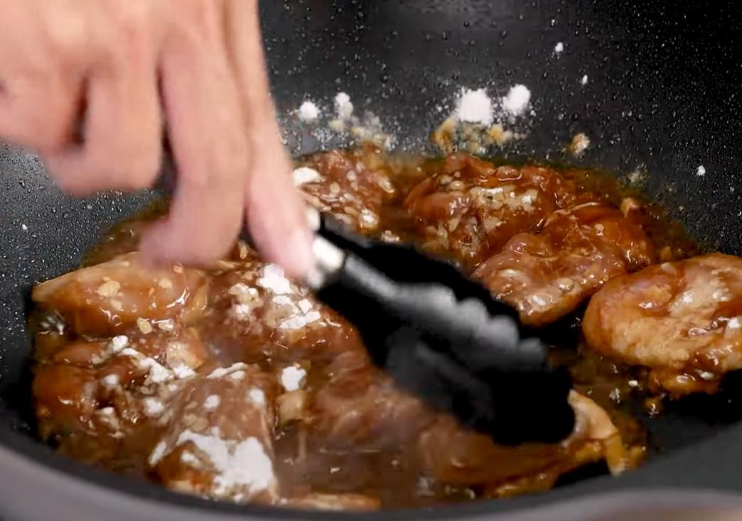 利用原鍋的雞油，放入醃好的雞腿肉煎上色，撒上玉米粉拌勻增加稠度。
