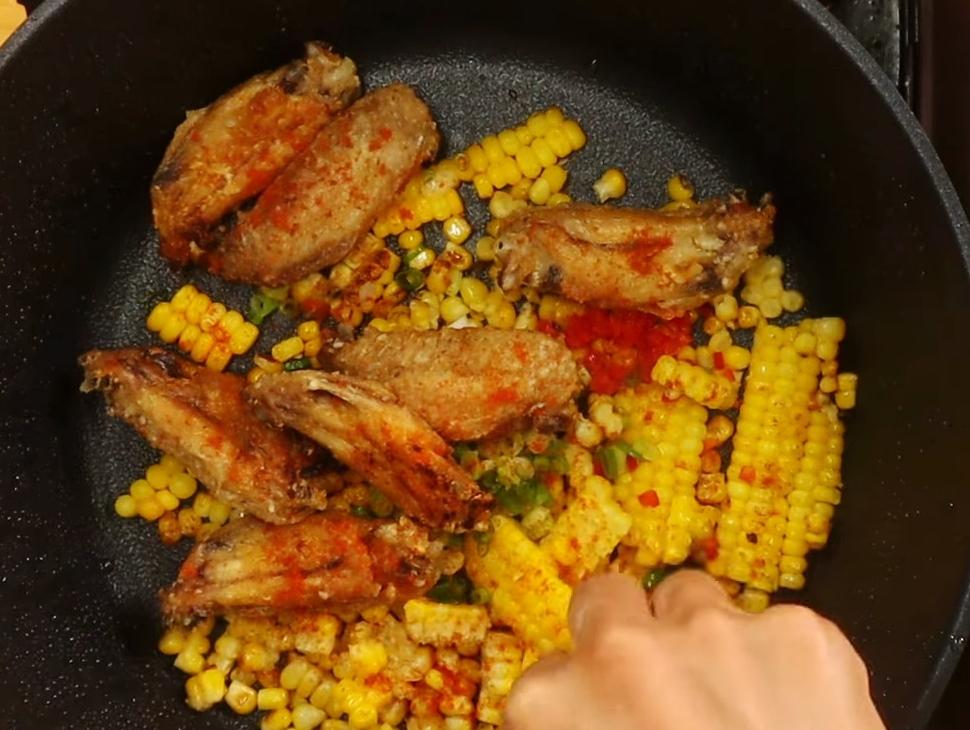 加入蔥花、辣椒碎、炸好的雞翅拌勻後關火，撒上辣椒粉、孜然粉、白胡椒拌勻即可起鍋。