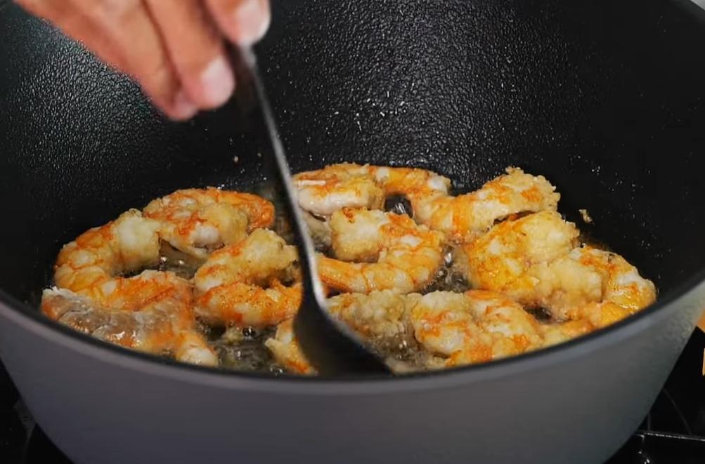 鍋中倒入略多的油，放入蝦仁半煎炸至兩面金黃。