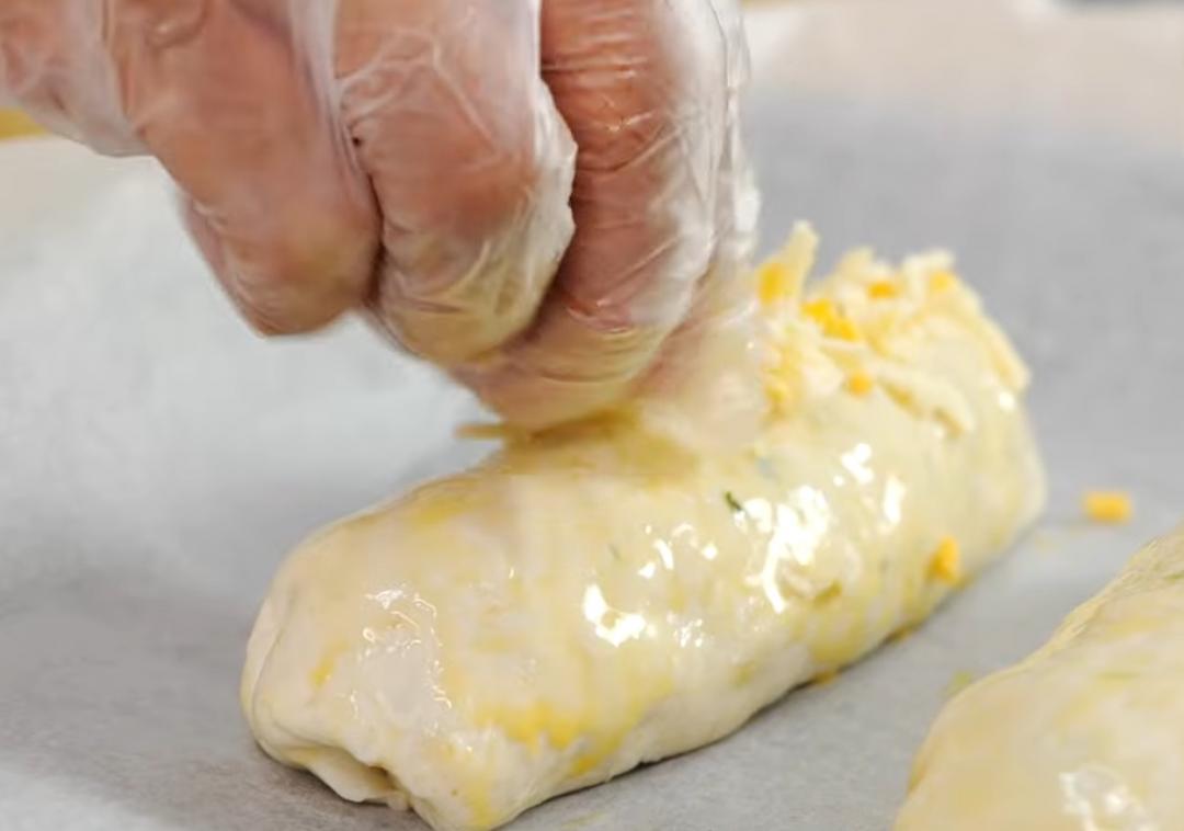 封口處捏緊後收口朝下放在烤盤上，塗上少許蛋液並撒上起司絲。放入烤箱設定170度烤15分鐘，完成。