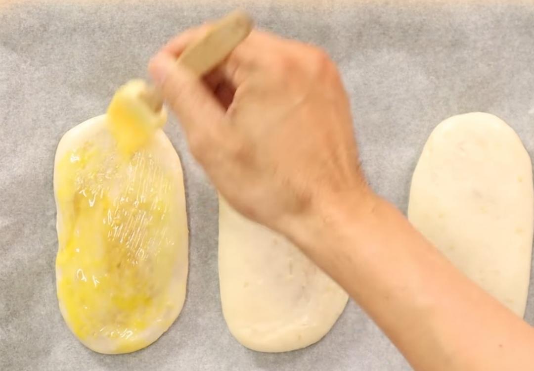 收口處朝下放上鋪有烘焙紙的烤盤中，刷上蛋液撒上黑芝麻。