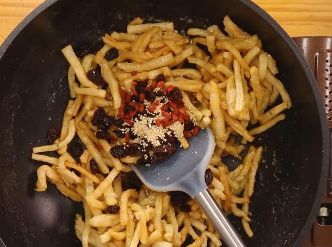熄火後,加入炸好的抓餅趁熱快速攪拌均勻,接著放葡萄乾、枸杞、白芝麻一起加入拌勻。