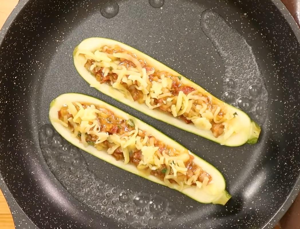 把櫛瓜「皮面朝下」放進平底鍋，鍋邊倒入約80ml水（或高湯），先煮至水滾後蓋鍋蓋，小火燜煮8至10分鐘，待起司融化後，掀蓋收汁，開大火讓底部稍微焦香即可盛盤。