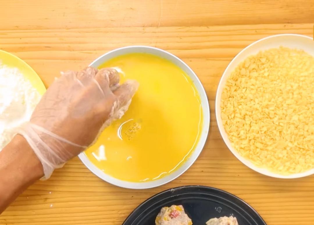 取適量蝦皮攤平，中間放入起司絲，之後包起搓成圓球狀。蝦球依序沾裹上玉米粉、蛋液、洋芋片。