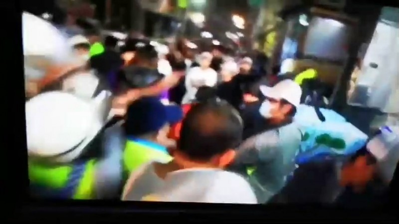 中天記者陳勝偉（戴口罩和鴨舌帽）在人群中拍攝現場畫面。（記者張聰秋翻攝）