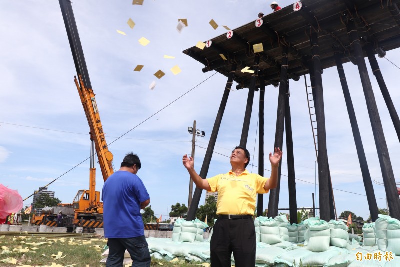 頭城中元祭典協會理事長楊碧村（右）於飯棧重新架設前，灑銀紙祭拜好兄弟。（記者林敬倫攝）