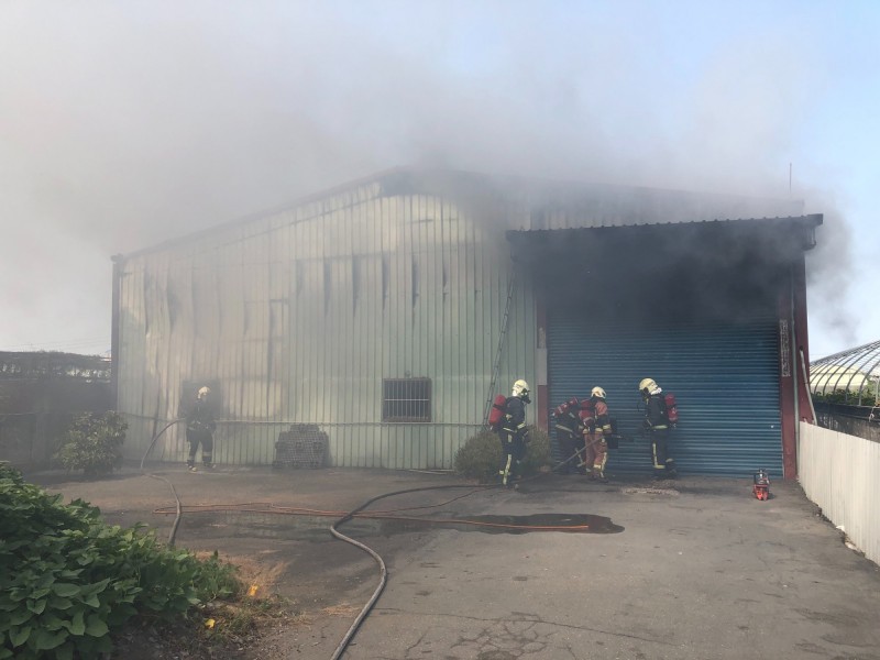 木材工廠起火，假日無人應門，消防人員準備重機具破門進入滅火。（記者陳冠備翻攝）