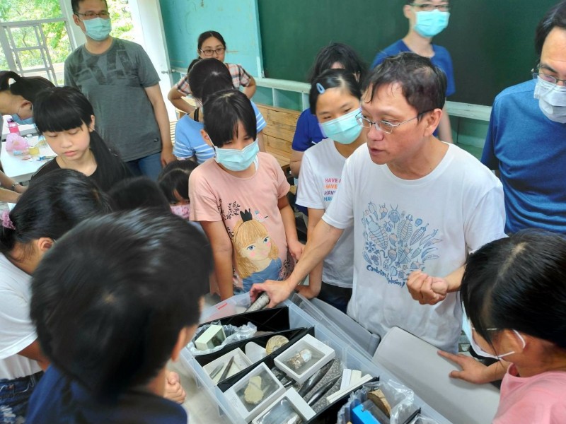 楊慶鴻（白衣者）向學生解說化石奧秘。（記者洪臣宏攝翻）
