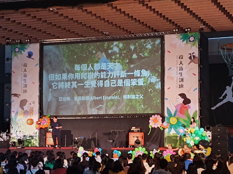 政大學生會長致詞時表示,「愛因斯坦曾經說過:『每個人都是天才。但如果你用爬樹的能力評斷一條魚,它將終其一生覺得自己是個笨蛋』」。此時,他背後的圖片,則是放出日前韓國瑜視察登革熱,親自爬上大樹的照片。(讀者褚人輔獨家提供) 政大學生會長致詞時表示,「愛因斯坦曾經說過:『每個人都是天才。但如果你用爬樹的能力評斷一條魚,它將終其一生覺得自己是個笨蛋』」。此時,他背後的圖片,則是放出日前韓國瑜視察登革熱,親自爬上大樹的照片。(讀者褚人輔獨家提供)