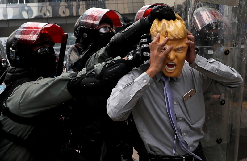 香港社運人士楊繼昌頭戴川普頭套被警方抬走逮捕。（路透社）