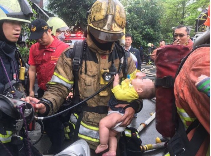 今早板橋公寓發生火災，消防員從火場中一手抱出嬰兒，被網友拍下感動一幕PO網。（圖擷自臉書爆料公社）
