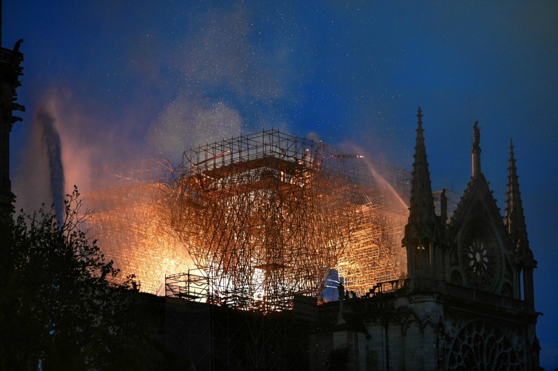法國巴黎聖母院於當地時間15日傍晚發生大火，當局雖緊急動員救災，教堂屋頂仍被大火燒毀崩落。（法新社）