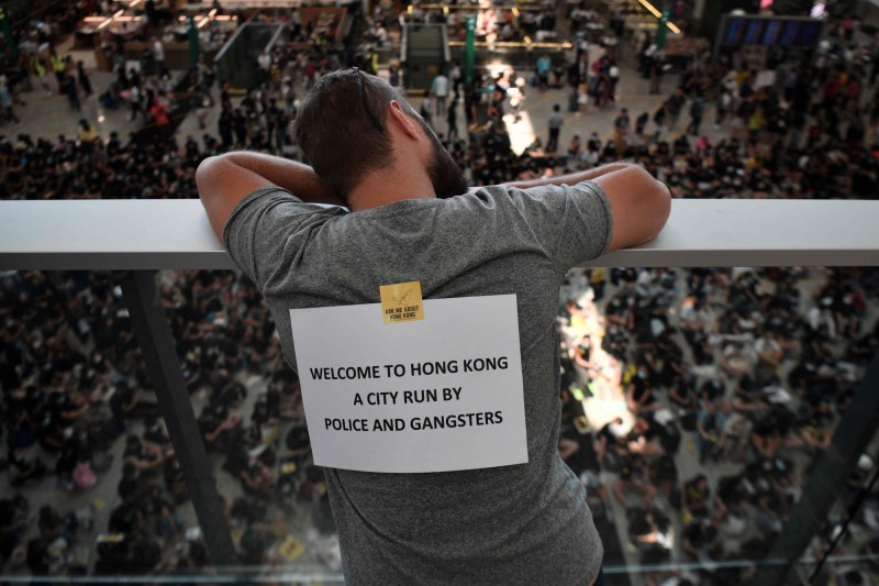 香港警方一連反對週末的4場遊行。圖為9日香港機場萬人接機活動中，一位民眾背後貼著「歡迎來到香港，一個由警察與黑幫管治的城市」的標語。（法新社）