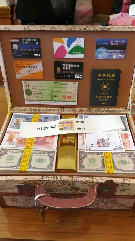 一名網友在掃墓時發現「環遊世界豪華皮箱」，內容物除了有護照、信用卡、支票外，還裝有滿滿的各國紙鈔。（圖擷取自爆料公社）