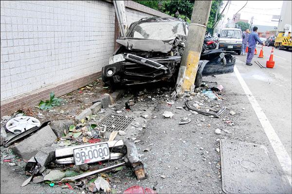 黑色汽車肇事逃逸後，又撞進2根電線桿中間空隙，車頭全毀動彈不得。（記者黃其豪攝）