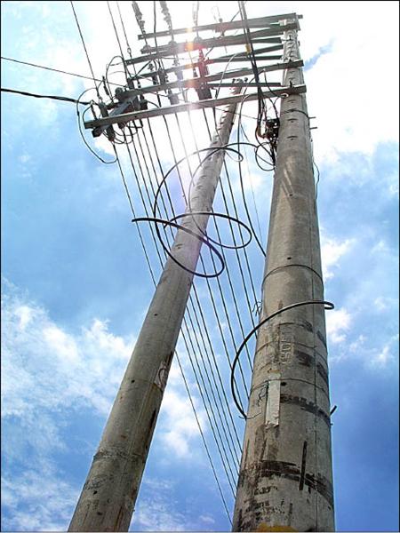 電線桿上的電線斷裂處處，有的還垂掛到地面上，是否安全也不無疑問。（記者羅正明攝）<br>