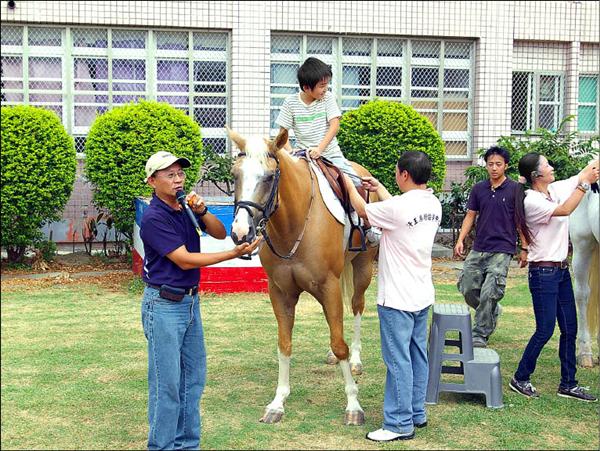 中華民國馬術協會秘書長李政憲（左）指導苗栗市文華國小小朋友騎馬注意事項。（記者陳界良攝）