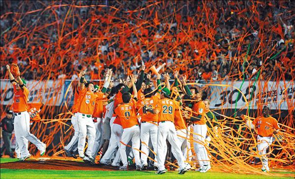 昨天中華職棒總冠軍賽第七戰統一獅以五比二擊敗兄弟象，完成三連霸，比賽結束剎那，橘色彩帶飄滿台南球場上空，球員興奮的互擁慶祝。（記者王藝菘攝）