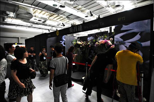 中山足球場改裝的爭豔館，昨天一早兩度斷電，館內缺乏空調悶熱不已，測試志工在昏暗會場內摸黑參觀。（記者方賓照攝）