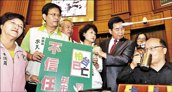 台中市ALA PUB大火案，市長胡志強未被彈劾，引起民進黨台中市議員不滿，昨在議會對胡志強提出「不信任案」，胡志強舉杯喝茶拒接海報。（記者詹朝陽攝）