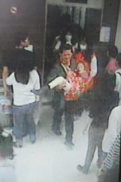 中年男子用大揹巾將媽媽抱在胸前，帶著母親到奇美醫院看醫就診。（記者林孟婷翻攝）