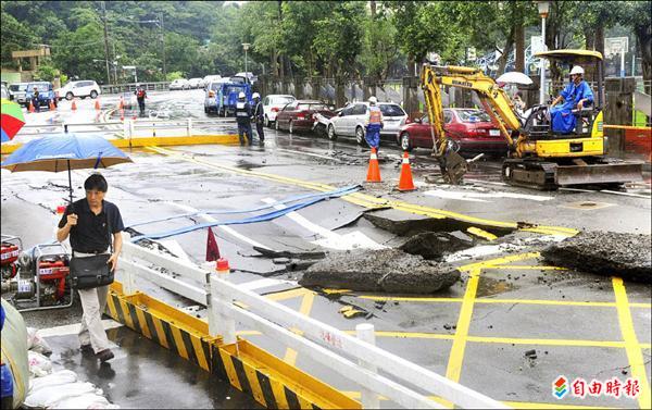 連夜豪雨，北市文山區萬芳路一處地下排水涵管爆裂，造成地面塌陷，工務人員封鎖該路段搶修。（記者羅沛德攝）