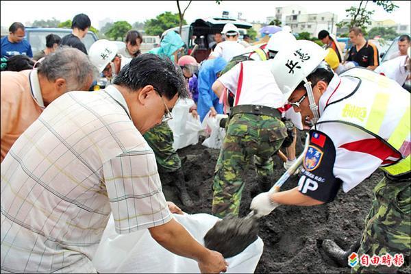 泰利颱風海陸警報雙響，預計颱風暴風圈在今天中午左右就會撞到台灣，全台都被劃進警戒區域，各地須防豪雨，圖為憲兵弟兄忙著挖沙，幫民眾裝成沙包備用。（記者林孟婷攝）