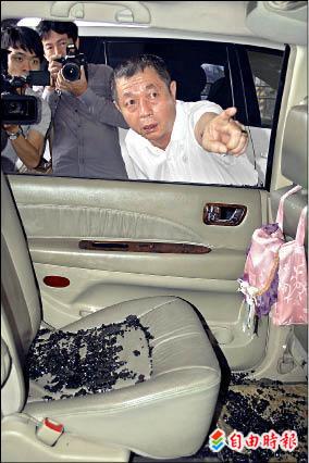 前議長周典論說明住宅遭槍擊時，彈道方向與彈著點，車窗玻璃碎落滿車。（記者黃良傑攝）