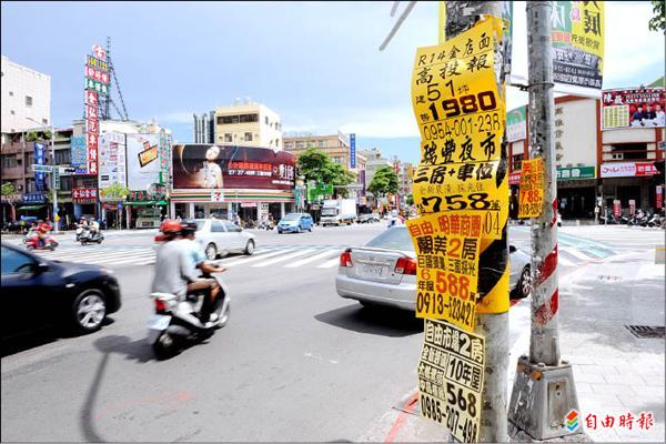 高雄市街頭上的電桿、交通號誌桿上貼滿房仲廣告，嚴重破壞市容，連日本遊客也看不下去。 （記者張忠義攝）