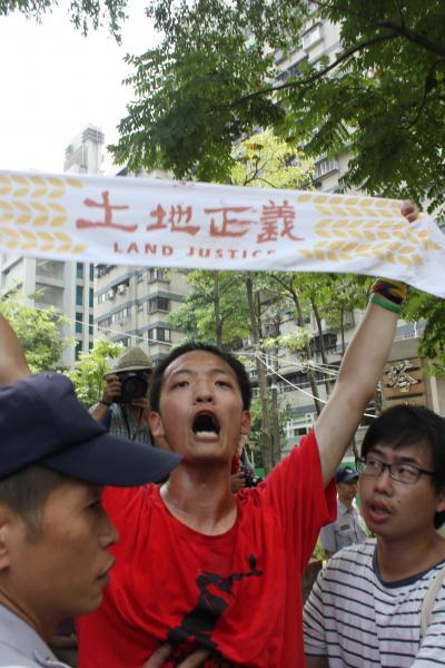 台大學生洪崇晏，高舉土地正義毛巾，疑遭警方撂倒撞破頭部，流血送醫。（記者邱宜君攝）