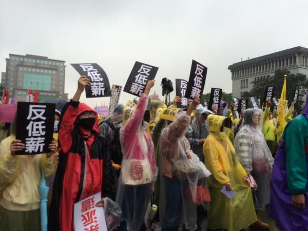 勞工們手持標語，已在凱道集結，不畏風雨上街頭。（記者陳炳宏攝）