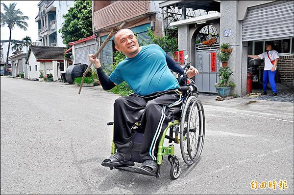 陳富貴坐在輪椅，拿竹子當標槍，在家門巷道練擲。（記者黃明堂攝）