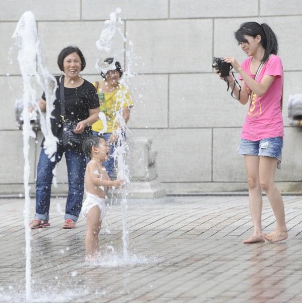 天氣高溫炎熱，民眾帶著孩子去玩水，炎炎夏日碰上冰冰的水，孩子都開心起來，家長幫孩子記錄下開心的一刻。（記者陳志曲攝）