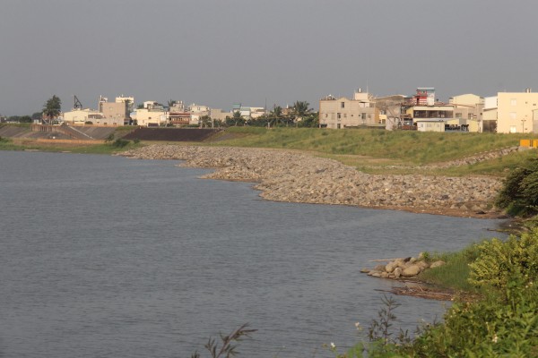 第六河川局在湖內區葉厝里河堤進行補強，在岸邊堆起石頭減緩水流沖刷。（記者陳祐誠攝）