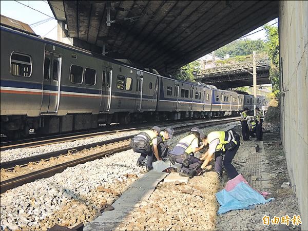 游姓男子坐在鐵道上，被台鐵區間車撞死，警察忙著覆蓋遺體。（記者林嘉東攝）