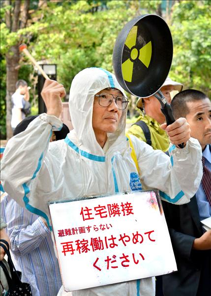 日本九州電力公司川內核電廠兩座機組十日通過安檢，多名反核民眾在原子能規制委員會前抗議，要求撤回。（法新社）