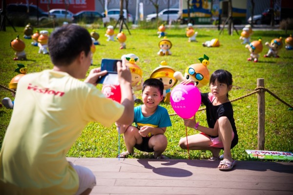 高雄市農業精靈「高通通」灑滿台中市政公園草地，感謝民眾購買農特產，為氣爆災民增添收益。
圖為民眾為小朋友拍照情形。（圖片由高雄市農業局提供）