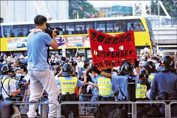 香港警方使用催淚彈驅散示威群眾時，不時高舉寫有「速離否則開槍」字眼的紅旗警告。（取自香港獨立媒體網）