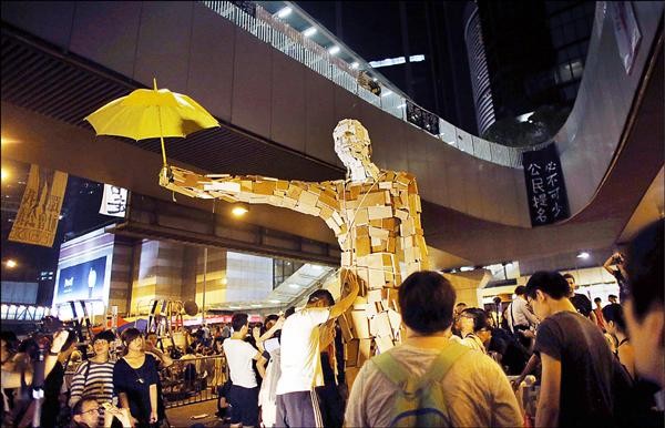 香港佔中抗議群眾5日豎起一個手持雨傘的巨型人像，封鎖通往中環的主街。（路透）