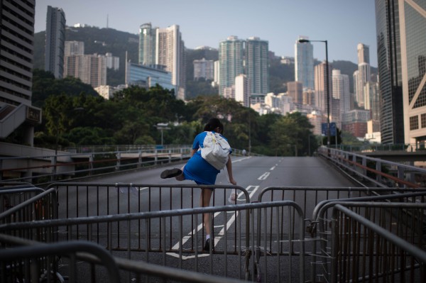 香港佔中行動持續，許多中小學生上下課因此受阻，許多學生還要翻過圍欄上學。（法新社）