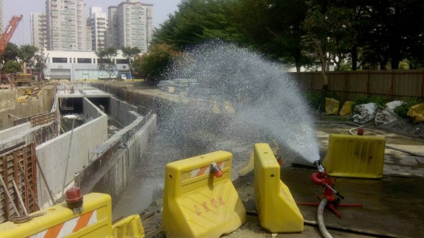 為保護消防員安全，漏氣工地現場以移動式砲塔灌水，人員在工地圍籬外警戒。（記者洪定宏攝）